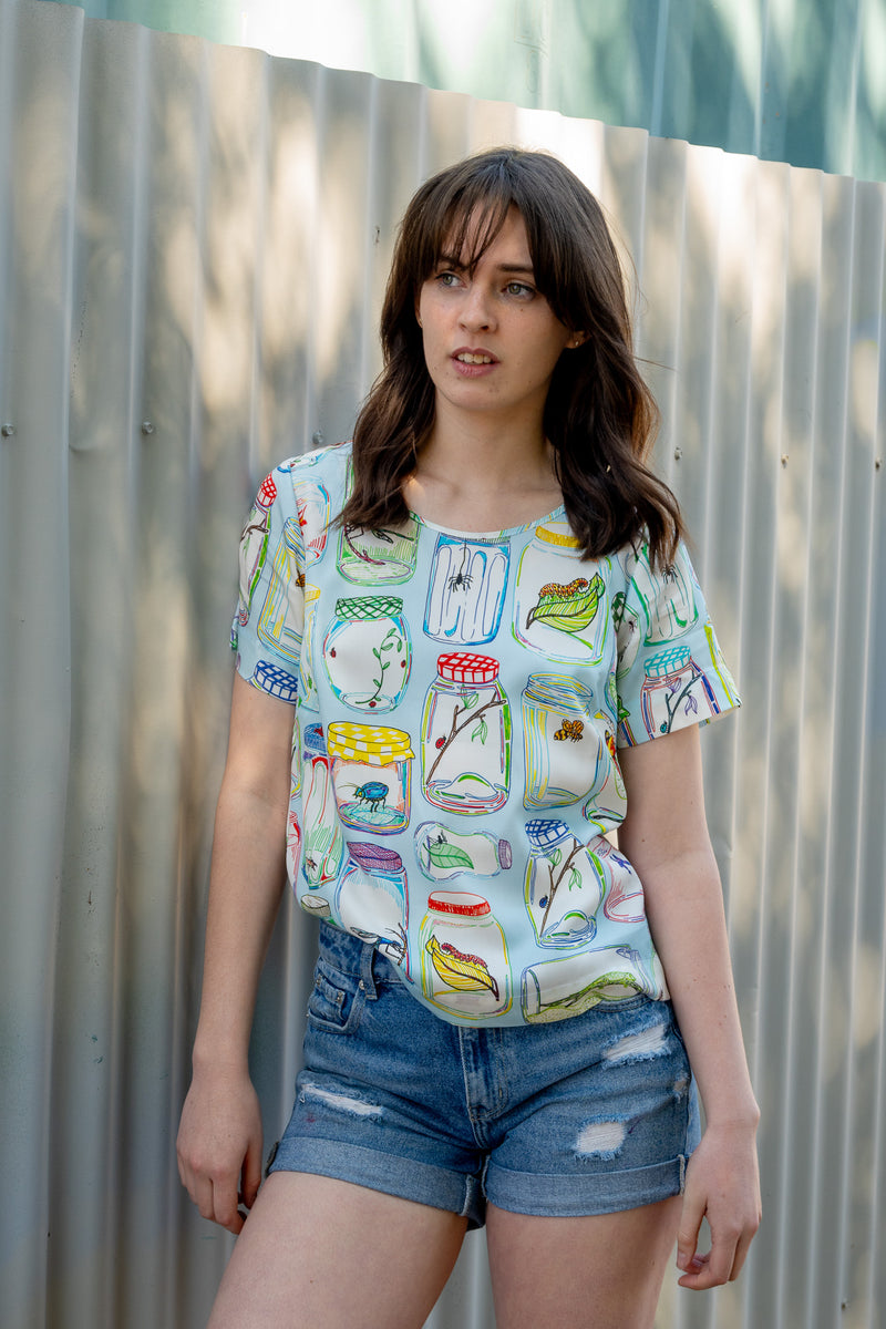 Pale blue top with colourful insects inside jars